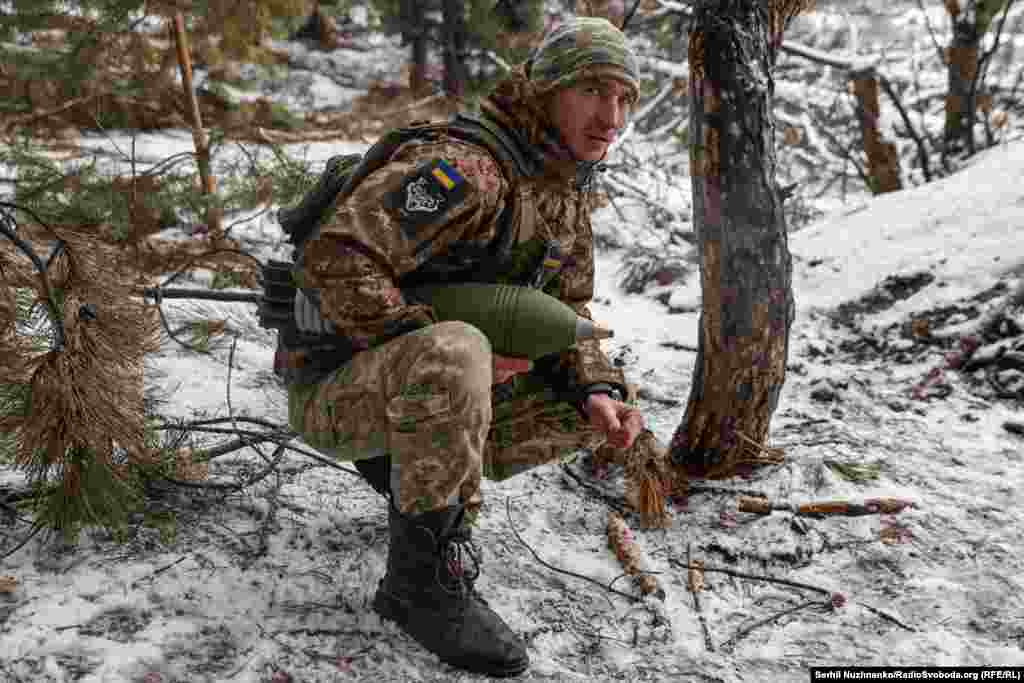 Український військовий тримає в руках 120 мм міну, очікуючи на координати. Куп'янський напрямок, січень 2024 року