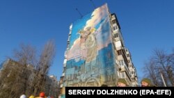 Українські військові та енергетики стоять перед муралом українським військам ППО та енергетикам. Київ, 30 листопада 2023 року