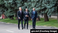 Președinții țărilor baltice - Gitanas Nausėda din Lituania (stânga), Alar Karis din Estonia și Edgars Rinkēvičs din Letonia - plimbându-se pe lângă un rând de pini din apropierea Casei Guvernului de la Chișinău, pe 27 august 2024
