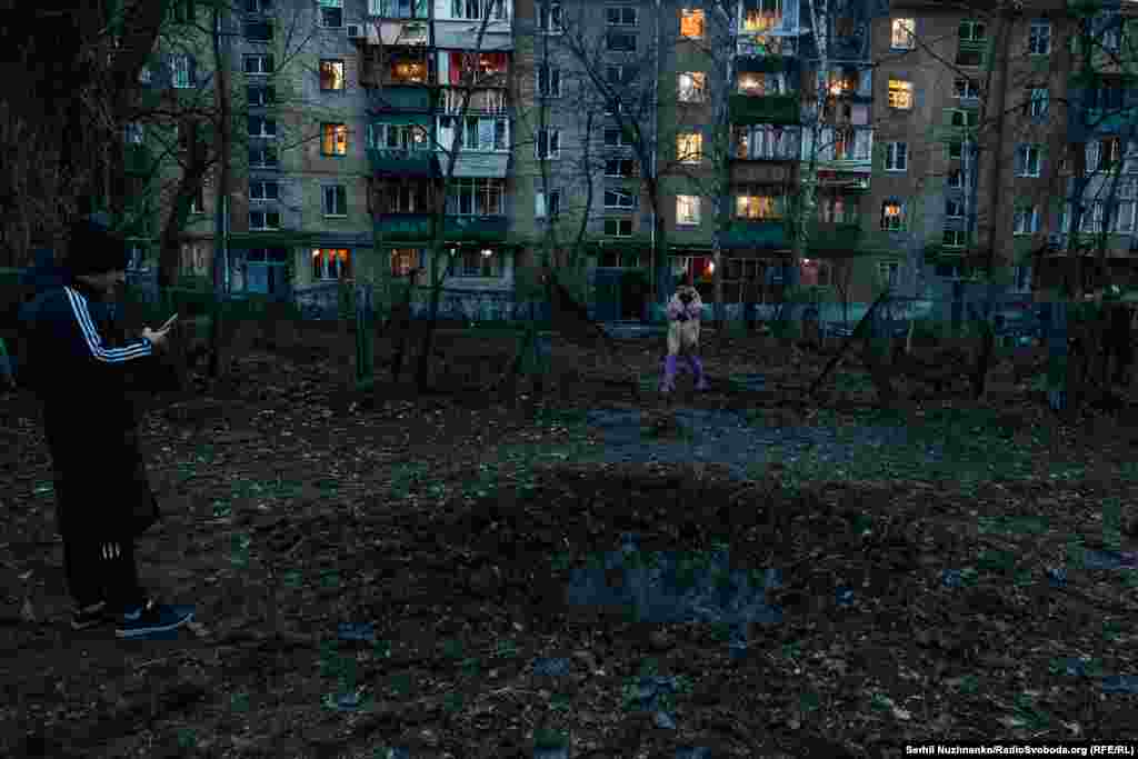 Місцеві  жителі стоять біля воронки, яка з’явилася після вибуху російського БПЛА «Шахед