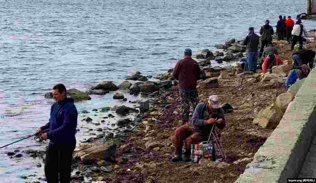 Керчане рыбачат не только на бетонной набережной, но и у кромки моря. Наиболее опытные рыбаки приносят с собой раскладные кресла – так и ноги не устают, и душевно пообщаться можно