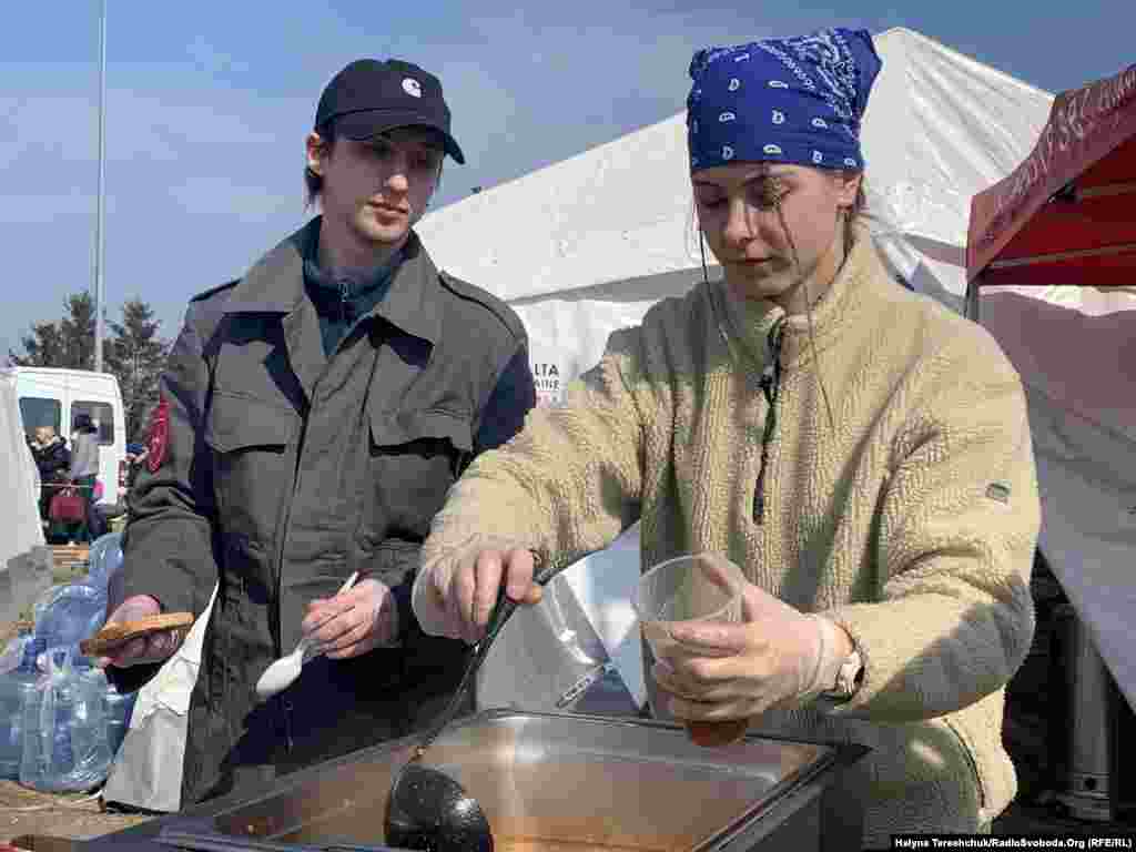 Волонтери «Мальтійської служби допомоги» ‒ Артур Бринзей із Івано-Франківська і Анна Лабай зі Львова – роздають біженцям їжу і гарячі напої. Молоді люди вирішили долучитись до допомоги, коли побачили багато дітей і жінок, які очікують у черзі