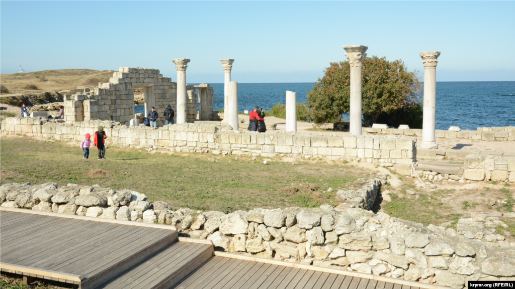 Туристы (в центре кадра) фотографируются на руинах древнего храма 
