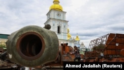 A child plays on top of an exhibition of destroyed Russian military vehicles and weapons outside St. Michael's Cathedral in Kyiv.