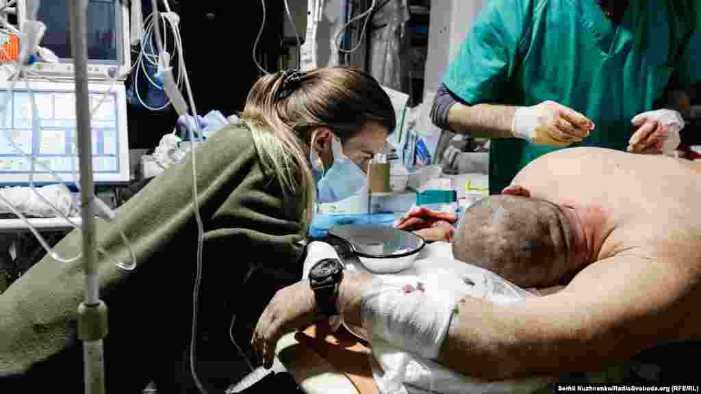 У той час, як воїну доводиться терпіти біль, одна із медикинь розмовляє із пораненим, намагаючись заспокоїти і підтримати. 