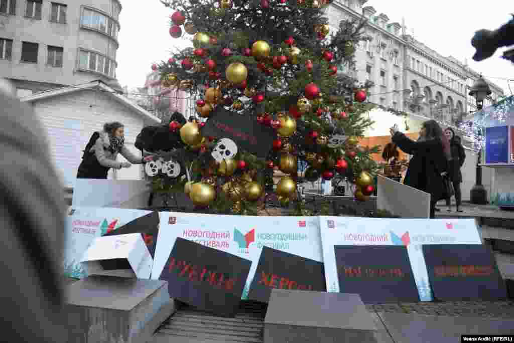 Maske su na kraju performansa okačili na rusku jelku, a transparente sa nazivima razorenih ukrajinskih gradova su ostavili ispod nje, kao poklone.  
