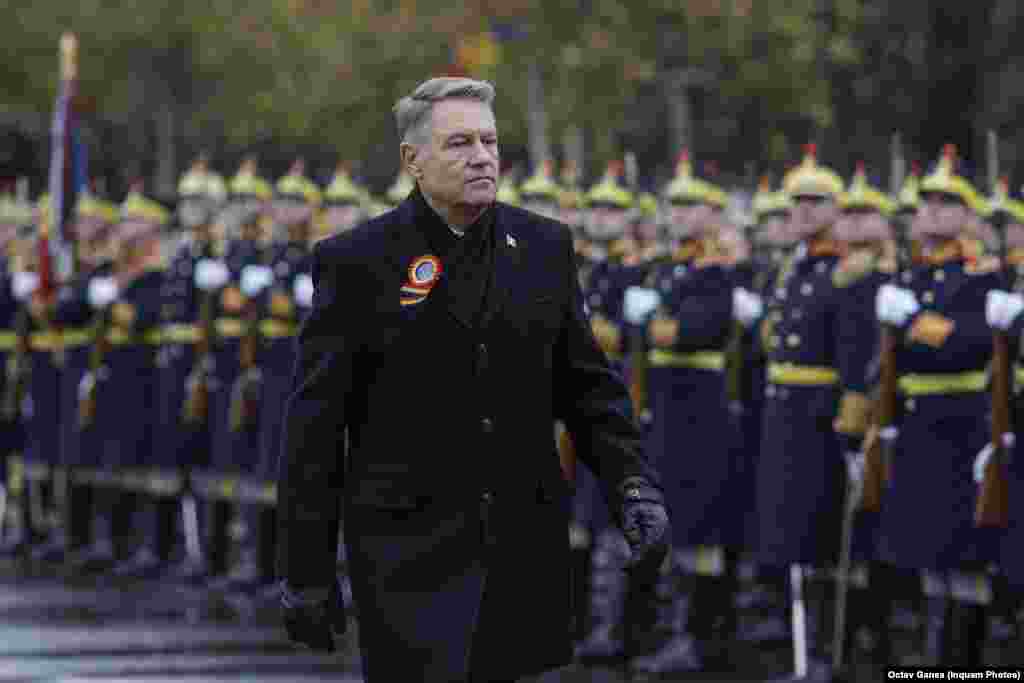 Președintele Klaus Iohannis, înfruntând vântul spre locul unde va primi onorul armatei de Ziua Națională a României.