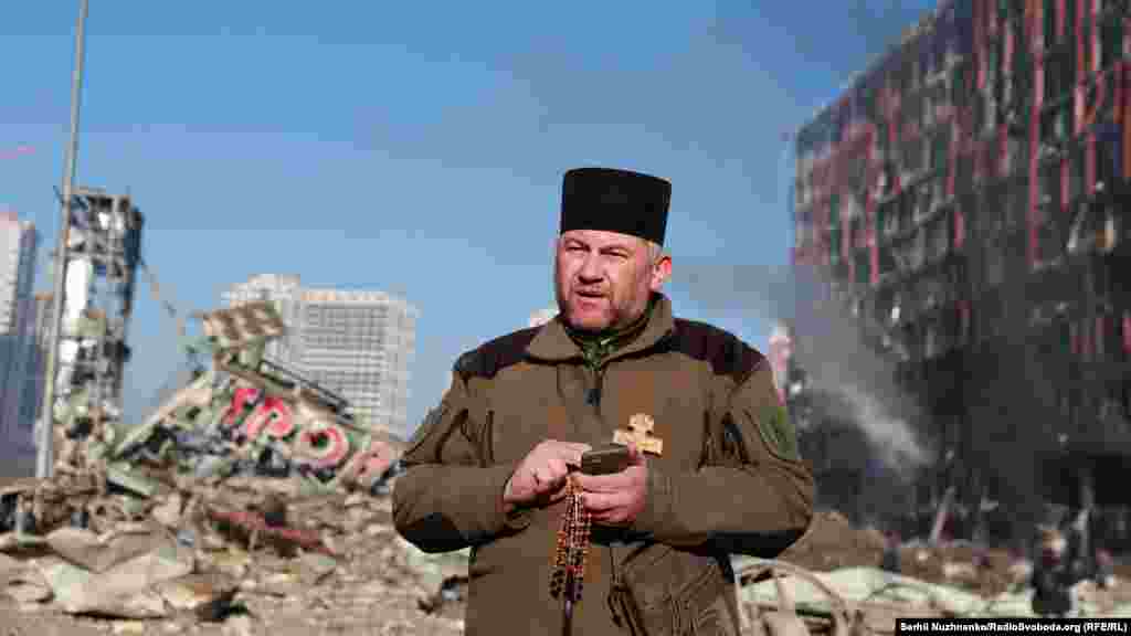 Капелан Микола Мединський прочитав молитву, пом'янаувши загиблих внаслідок російського обстрілу. Наслідки обстрілів Подільського району Києва, 21 березня 2022 року