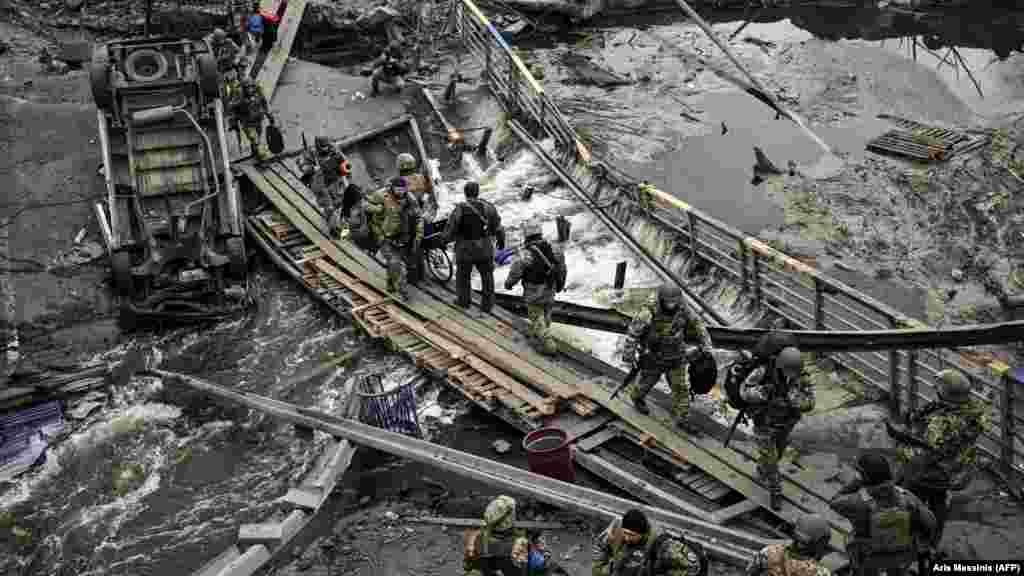 Військовослужбовці ЗСУ перетинають річку через зруйнований міст поблизу міста Ірпінь, 13 березня 2022 року