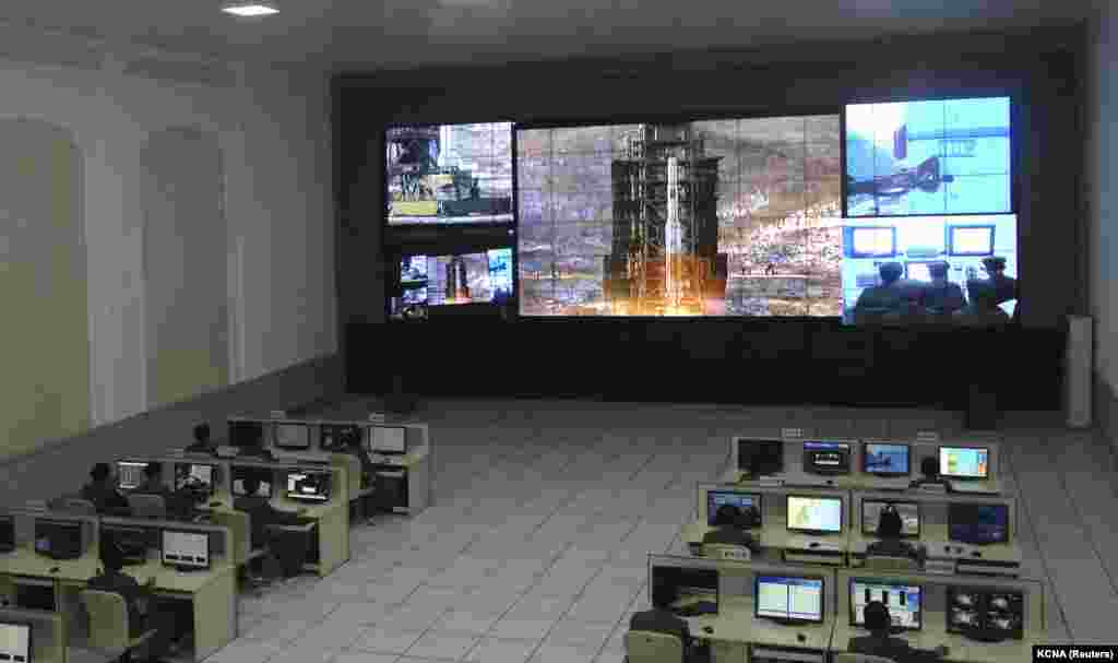 Shkencëtarët koreanoveriorë duke punuar, teksa një ekran shfaqte lëshimin e raketës "Unha-3". Fotografi e publikuar më 12 dhjetor 2012.