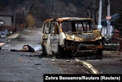 Тіло убитої російськими військовими цивільної людини та спалений автомобіль на вулиці Бучі. 2 квітня 2022 року