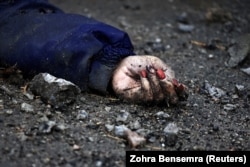The body of a woman, who residents say was killed by Russian soldiers, lies on the street in Bucha in April 2022.