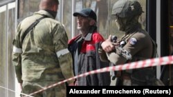 Мужчина, покинувший территорию «Азовстали» в Мариуполе, разговаривает с военнослужащими российских войск возле пункта временного размещения в селе Безыменное Донецкой области, Украина, 1 мая 2022 года