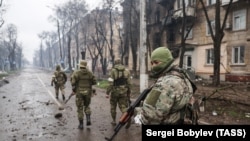 Російські військові ідуть зруйнованою вулицею Маріуполя. 13 квітня 2022 року