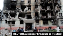 Місцеві жителі зібралися біля зруйнованого житлового будинку в Маріуполі, квітень 2022 року