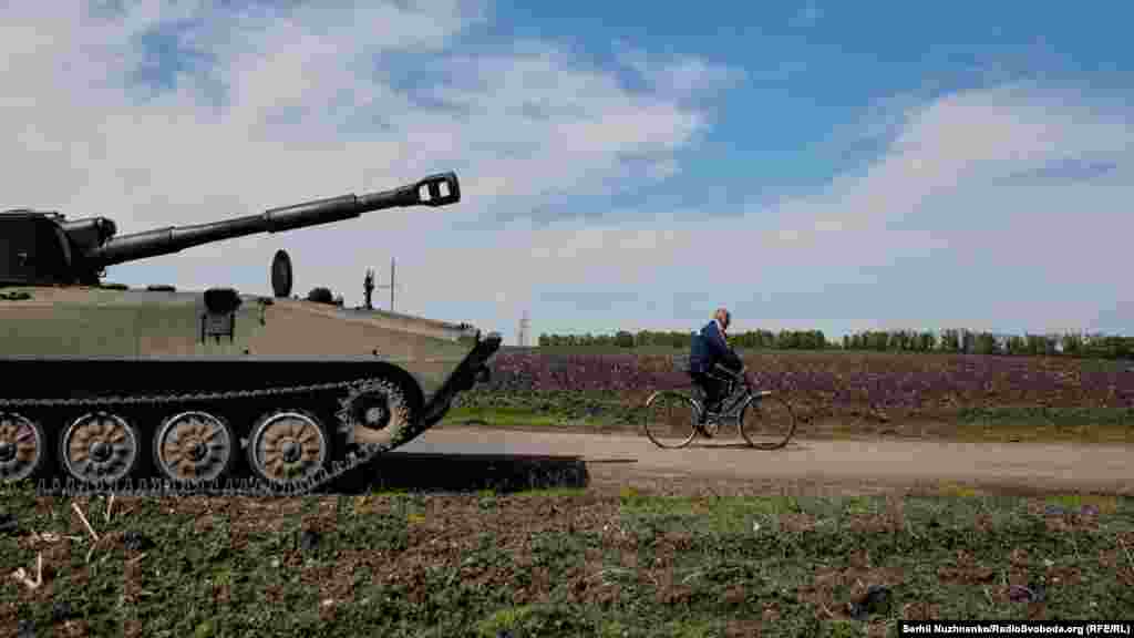 Местный житель проезжает на велосипеде мимо 122-мм самоходной артиллерийской установки 2С1 «Гвоздика». Харьковская область, 7 мая 2022 года