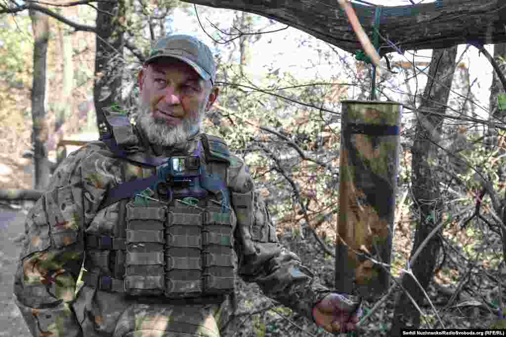 «Я Славік, мені 48, на повномасштабній війні з перших днів, в цивільному житті займався корпусними меблями, на гарматі я заряджаючий» – так представився військовий із сивою бородою, як у морського капітана. На цьому фото він показує символічний дзвін – такий, як ті, що є на кораблях, але зроблений зі стріляної гільзи. «Буває, по кілька днів не спиш, можеш команду не почути, а це чують всі», – каже він з усмішкою