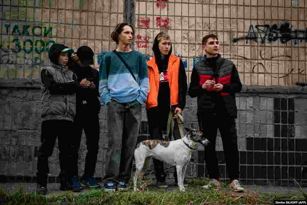 Підлітки дивляться на наслідки російських обстрілів їхнього міста.  Щонайменше 16 українських міст зазнали ракетних та дронових атак. Багато з цих міст не обстрілювалися Росією з весни цього року