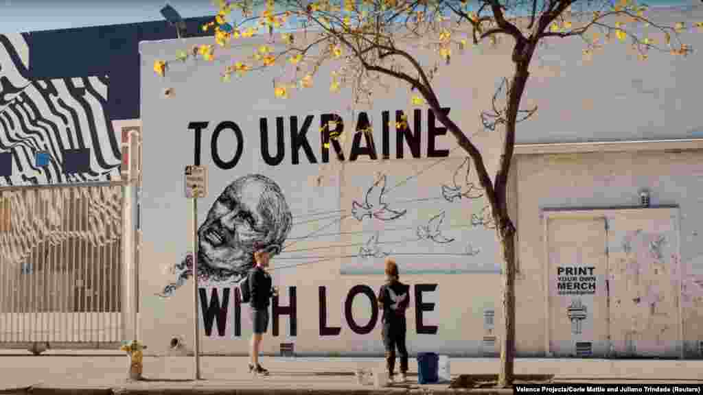 Художники Джуліано Тріндаде та Корі Метті з Valence Projects стоять перед своїм спільним муралом «Україні з любов'ю» у Лос-Анджелесі 8 травня. Метті сказала Радіо Свобода, що хотіла зобразити символ надії, коли голуби забирають владу Путіна. «Я думаю, що будь-яке мистецтво може змінити ситуацію», – сказала вона. «Це змушує глядачів думати про поточну ситуацію, змінювати погляди і навіть спонукати людей діяти». На цій конкретній фресці є QR-код, який відправляє до створеного Національним банком України фонду підтримки української армії. «Важливо надати людям можливість бути активними. Гарне мистецтво змушує вас думати, але велике мистецтво змушує вас діяти», – сказала Метті.