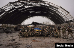 Українські військові перед ангаром зі спаленою від російської бомби чи ракети «Мрією» у звільненому наприкінці березня 2022 року Гостомелі під Києвом