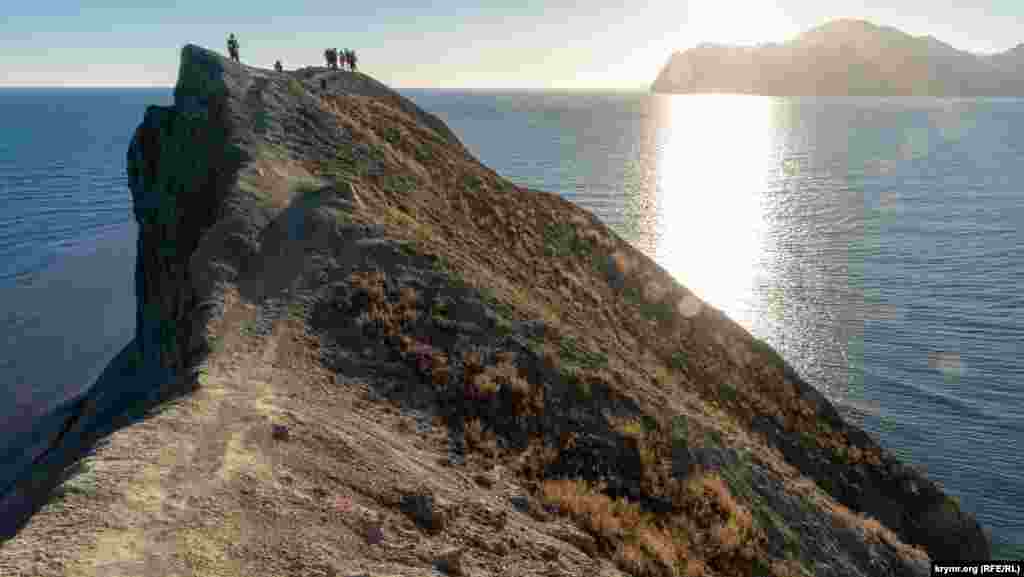 Туристы на гребне мыса Хамелеон, длина которого составляет 70 метров. Максимальная высота мыса – 62 метра Завораживающие виды и «мертвый» сезон в бухтах Коктебельского залива смотрите в фотогалерее