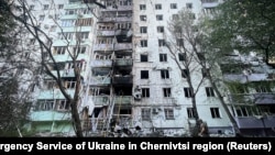 Pompieri și un polițist intervin la locul unui bloc de locuințe avariat în urma atacurilor rusești asupra Cernăuțiului, Ucraina, 12 iulie 2025.