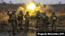 Українські військові позують для фото під час ведення вогню по російських позиціях із самохідної артилерійської установки на передовій у Харківській області, 24 грудня 2022 року