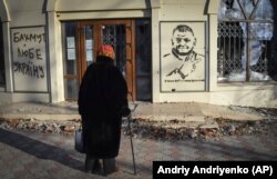 Жінка дивиться на графіті із зображенням головнокомандувача ЗСУ та написом «З нами Бог і отаман Залужний» у Бахмуті