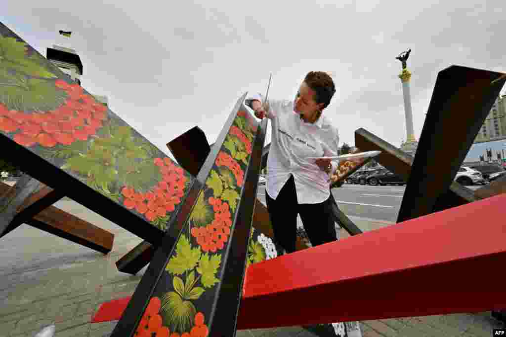 Украинская художница Варвара Логвин разрисовывает противотанковые заграждения, известные как «чешские ежи», традиционной украинской петриковской росписью. Киев,15 августа 2022 года