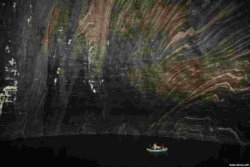 Туристы сидят в лодке на подземном озере в Салина Турда, бывшей соляной шахте, которая превратилась в туристическую достопримечательность в центральной Румынии. В настоящее время он внесен в список экстренных служб как потенциальное убежище гражданской обороны Румынии.  