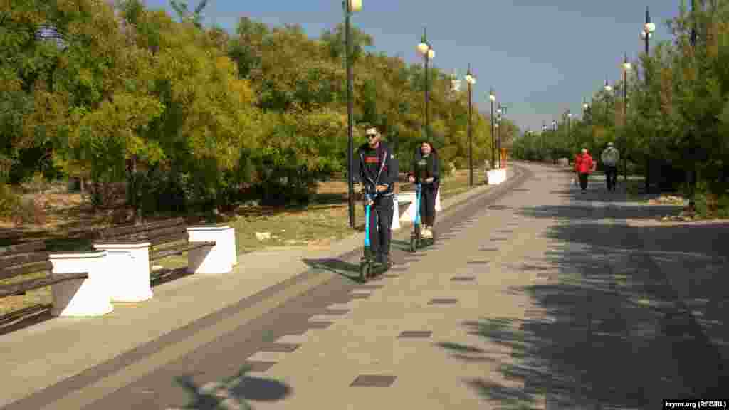 Мужчина и женщина едут «в колонне» по правой стороне пешеходной дорожки Парка Победы