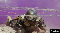 An Iraqi soldier crawls through colored smoke and barbed wire during a training course at a military base south of Baghdad on August 30. Iraqi security forces are now responsible for combat operations in the country.