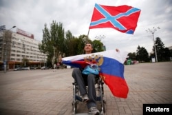Чоловік тримає прапор так званої «Новоросії» (зверху) і Росії (внизу) під час мітингу на площі Леніна в окупованому Донецьку, 13 липня 2014 року