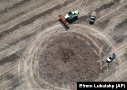 Воронка від влучення російської ракети на українському полі за десяток кілометрів від лінії фронту, де точаться запеклі бої. Україна, 4 липня 2022 року