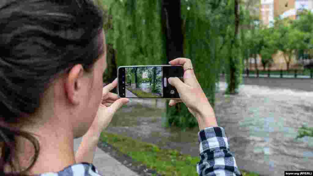 Девушка снимает  разбушевавшуюся реку