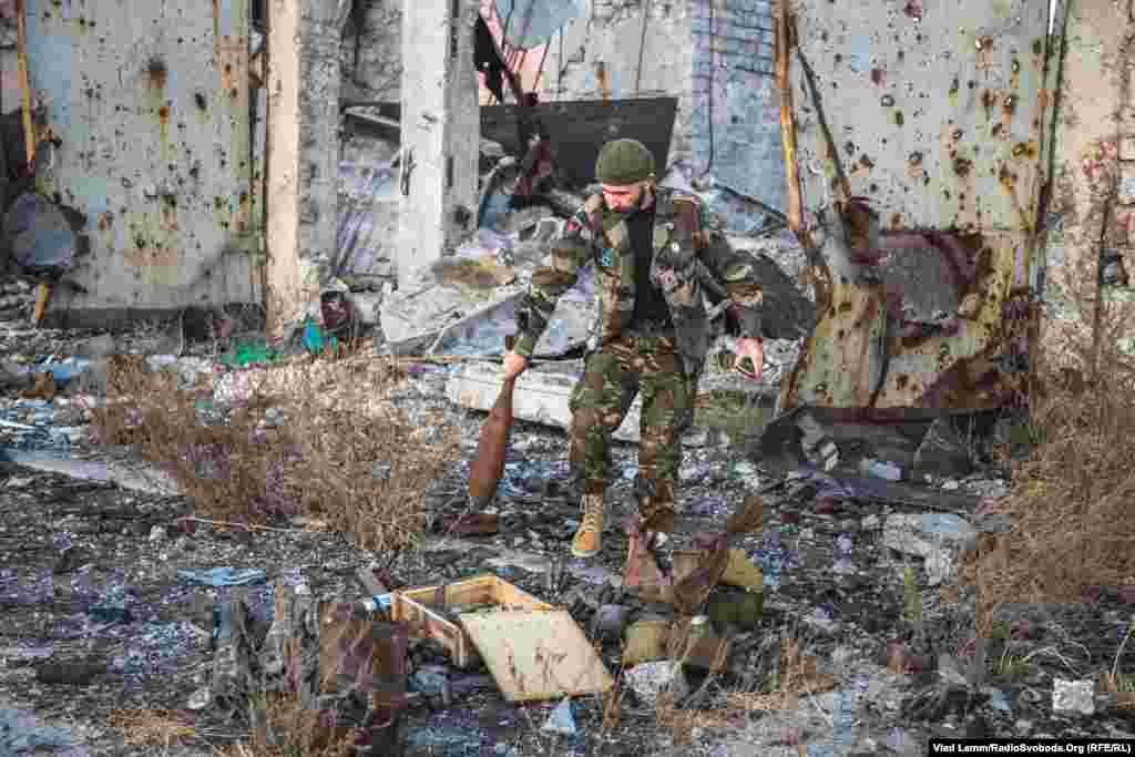 Волонтер Юрій дістає з-під завалів нерозірвану мінометну міну. Довкола лежить багато нерозірваних та непридатних для використання боєприпасів