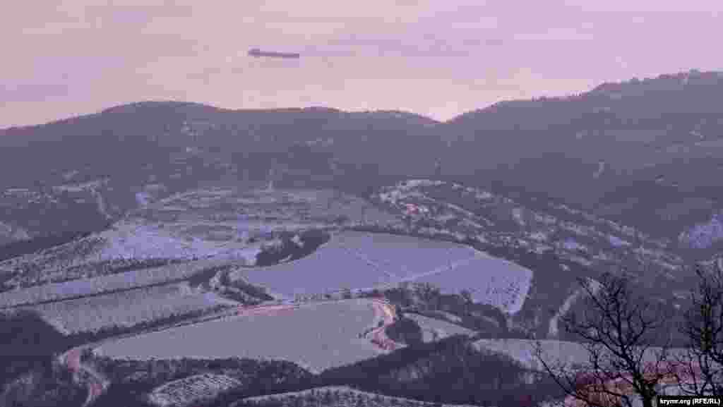 Заснеженные виноградники на приморских отрогах Демерджи-яйлы. Среди них просматривается автодорога, соединяющая шоссе Симферополь-Ялта и Судак-Алушта через Лучистое