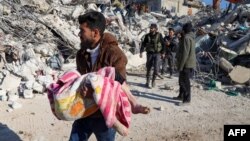 Un bărbat cară trupul unui copil scos dintre dărâmături în orașul Harim, în provincia siriană Idlib, aflată în nord-vestul țării și controlată de rebeli, 8 februarie 2023.