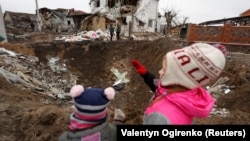 Діти дивляться на воронку, яка залишилася внаслідок російського ракетного удару в селищі міського типу Глевасі на Київщині, 26 січня 2023 року (ілюстраційна світлина)