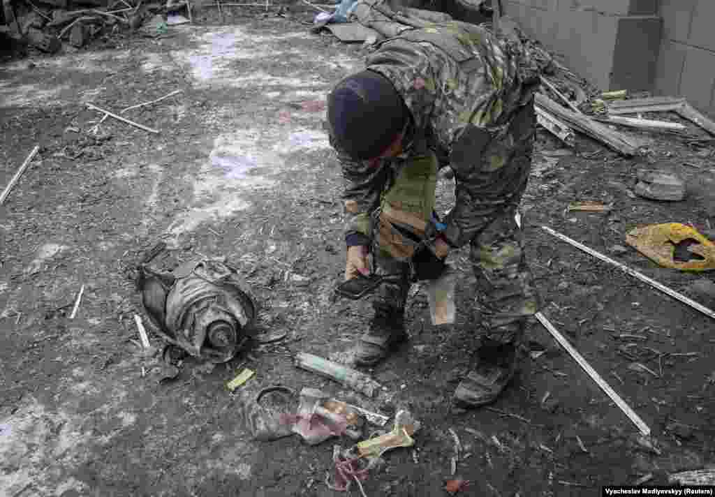 Поліцейський збирає для доказів залишки російської ракети біля житлового будинку, зруйнованого ударом «Іскандера» по Краматорську, 2 лютого 2023 року