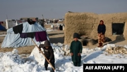 Afghan internally displaced children shovel snow near their tents during a cold winter day in the Nahr-e Shah-e district of Balkh Province on January 17.