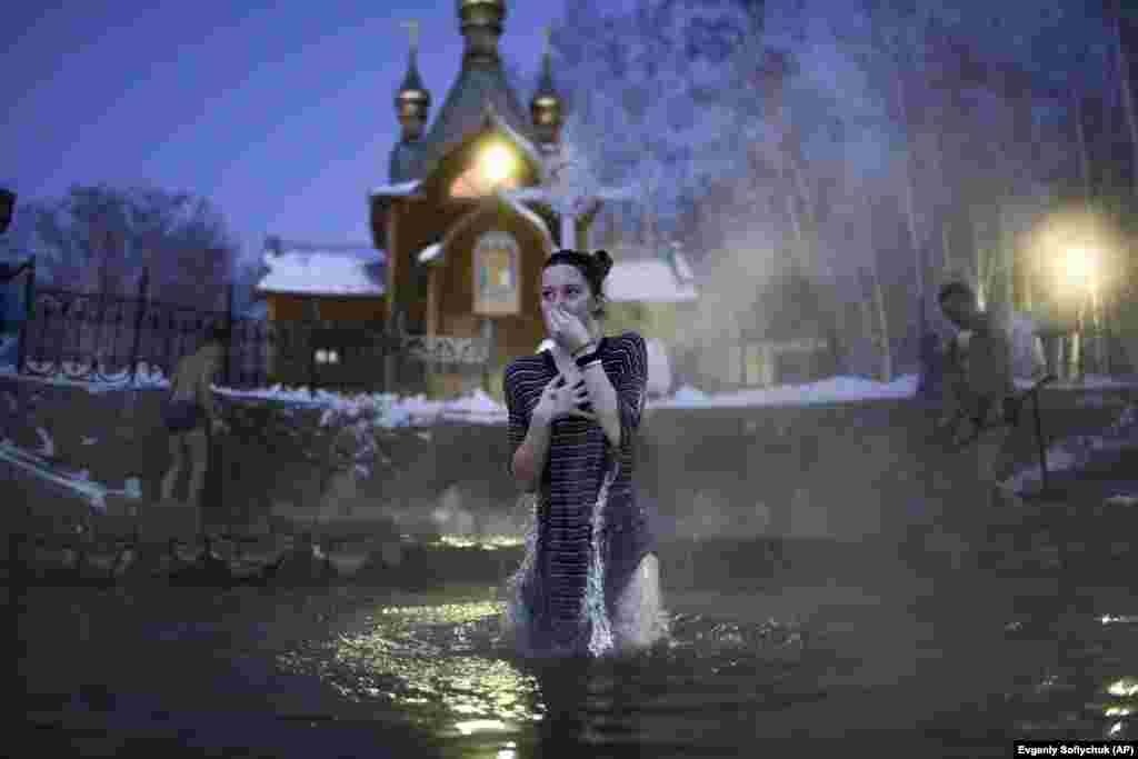 A woman reacts to the freezing water near the monastery in the early morning hours. The Epiphany is frequently marked by a dip in water to symbolize Christ's baptism in the River Jordan.  