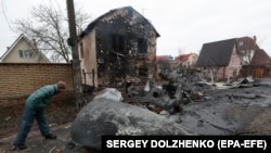 Чоловік дивиться на уламки військового літака, збитого вночі в Києві, Україна, 25 лютого 2022 року