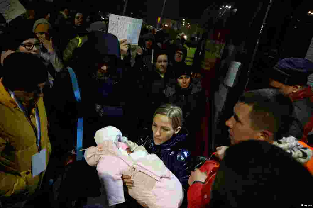 Широкомасштабне вторгнення Росії в Україну примусило 13 мільйонів людей покинути свої домівки. За даними ООН, 5 мільйонів залишилися в Україні, в 8 – виїхали до інших країн. Більшість українських біженців спочатку потрапили у Польщу, де їм допомогли і продовжують допомагати.  На фото від 26 лютого 2022 року: біженці з України вийшли з автобуса у Перемишлі. Серед них і молода мама з немовлям, яке народилася кілька днів тому.