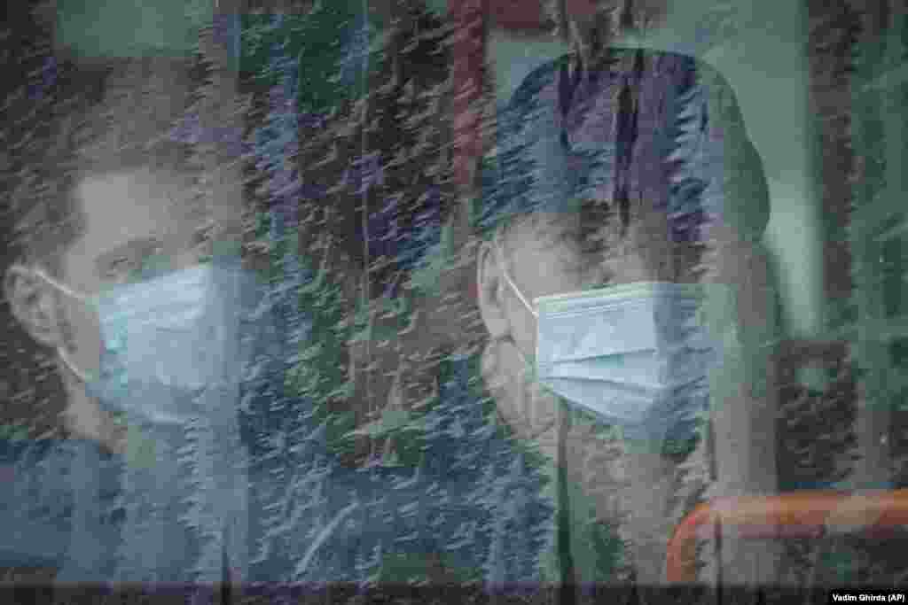 Пасажири автобуса спостерігають за протестом  медичних працівників, які вимагають покращення умов праці та зарплати біля будівлі уряду в Бухаресті, Румунія