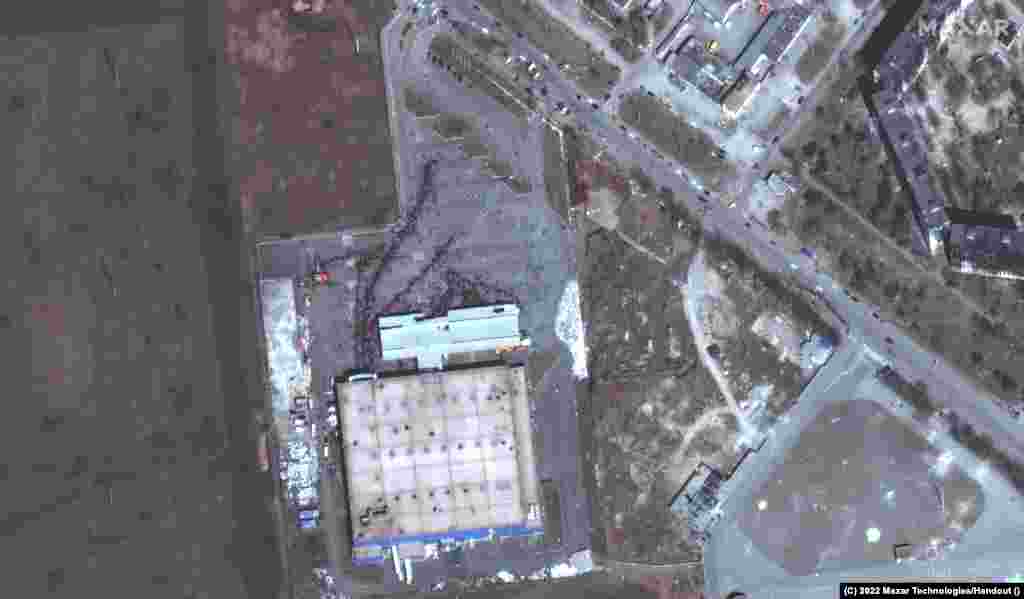 Гражданские жители заблокированного российской армией Мариуполя стоят в очереди за едой перед одним из последних уцелевших магазинов города, 29 марта 2022 года. Satellite image ©2022 Maxar Technologies. Российские войска не пропускают продовольствие, лекарства и другую помощь в Мариуполь