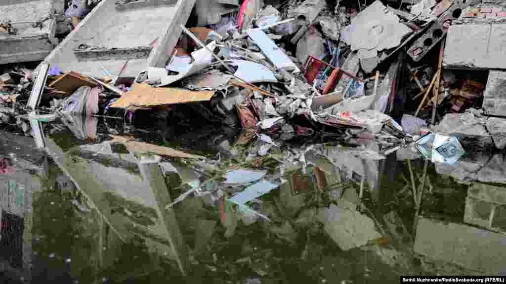 Заповнена водою вирва від потрапляння ракети і завали цивільного об'єкта. Бахмут, 4 червня 2022 року