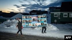 Жители несут предвыборный плакат. Нуук, Гренландия, 11 марта 2025