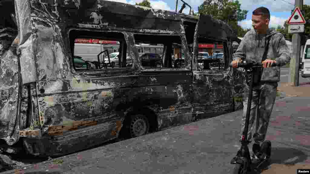 Ukrajinski dečak vozi trotinet pored vozila uništenog u ruskom napadu na ukrajinski grad Bila Cerkva u Kijevskoj oblasti.