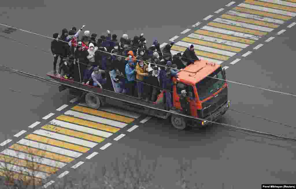 Demonstrators ride a truck in Almaty on January 5. One of the men is carrying a stick, another holds what appears to be a riot policeman's shield. 